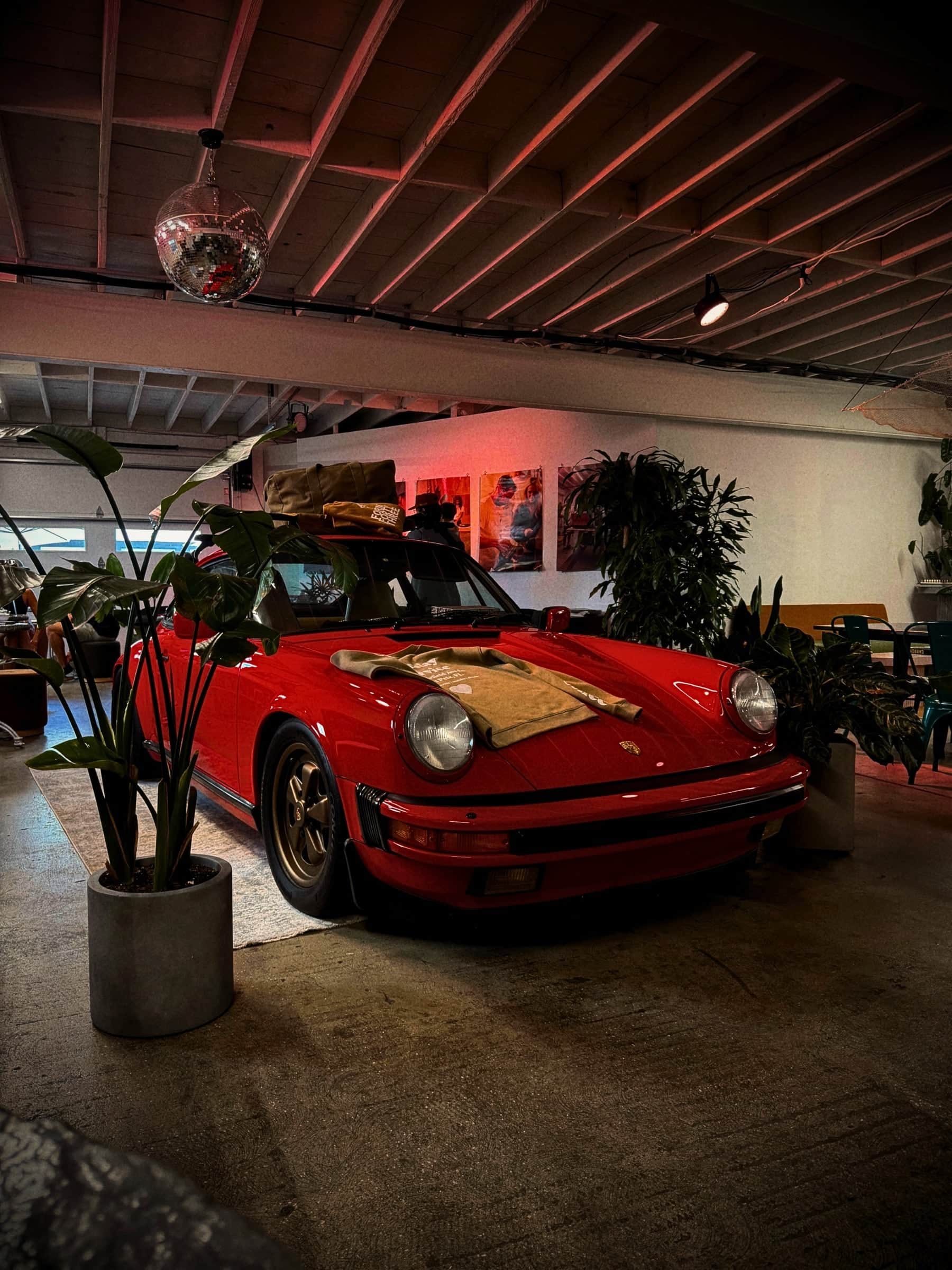 Vintage red Porsche displayed inside a moody café beneath a timber ceiling