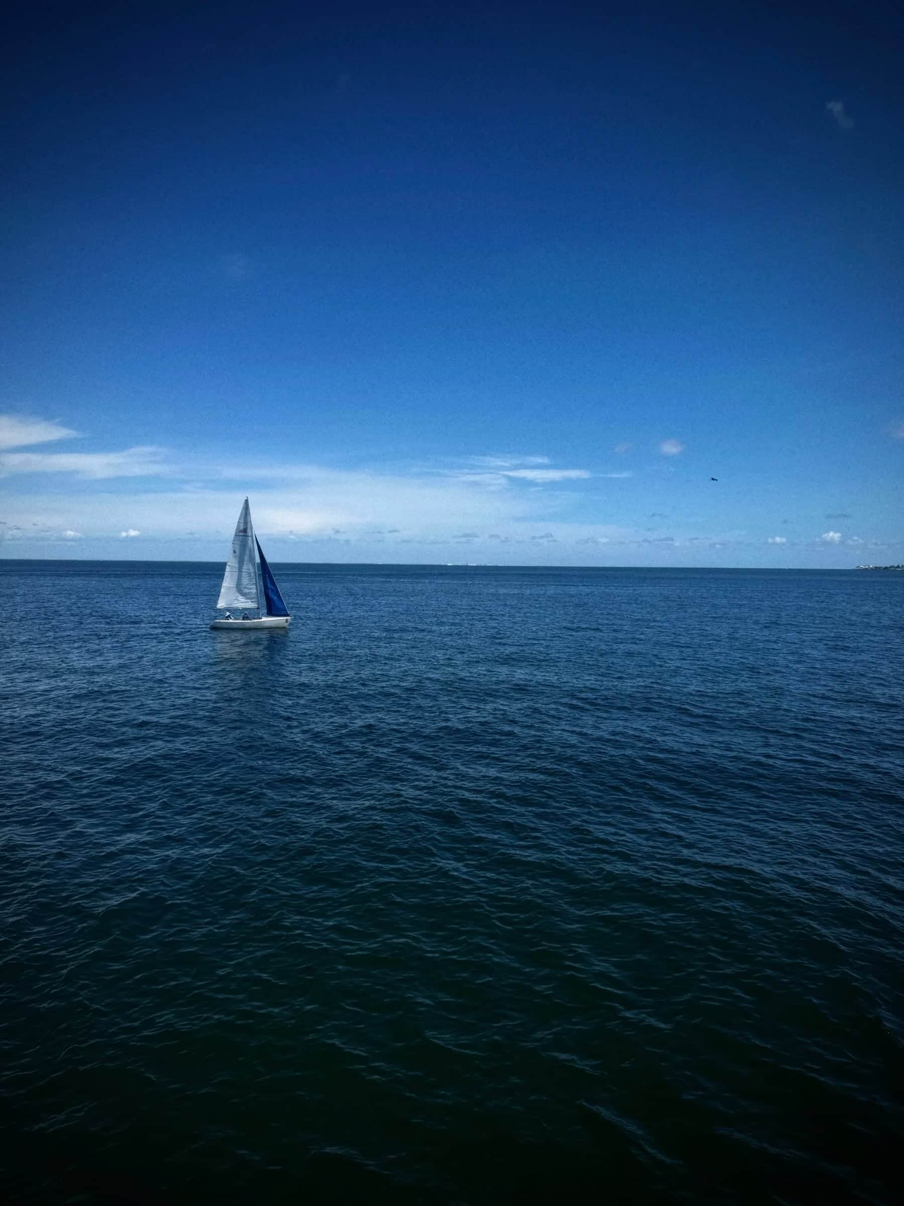 A lone sailboat on deep blue open water