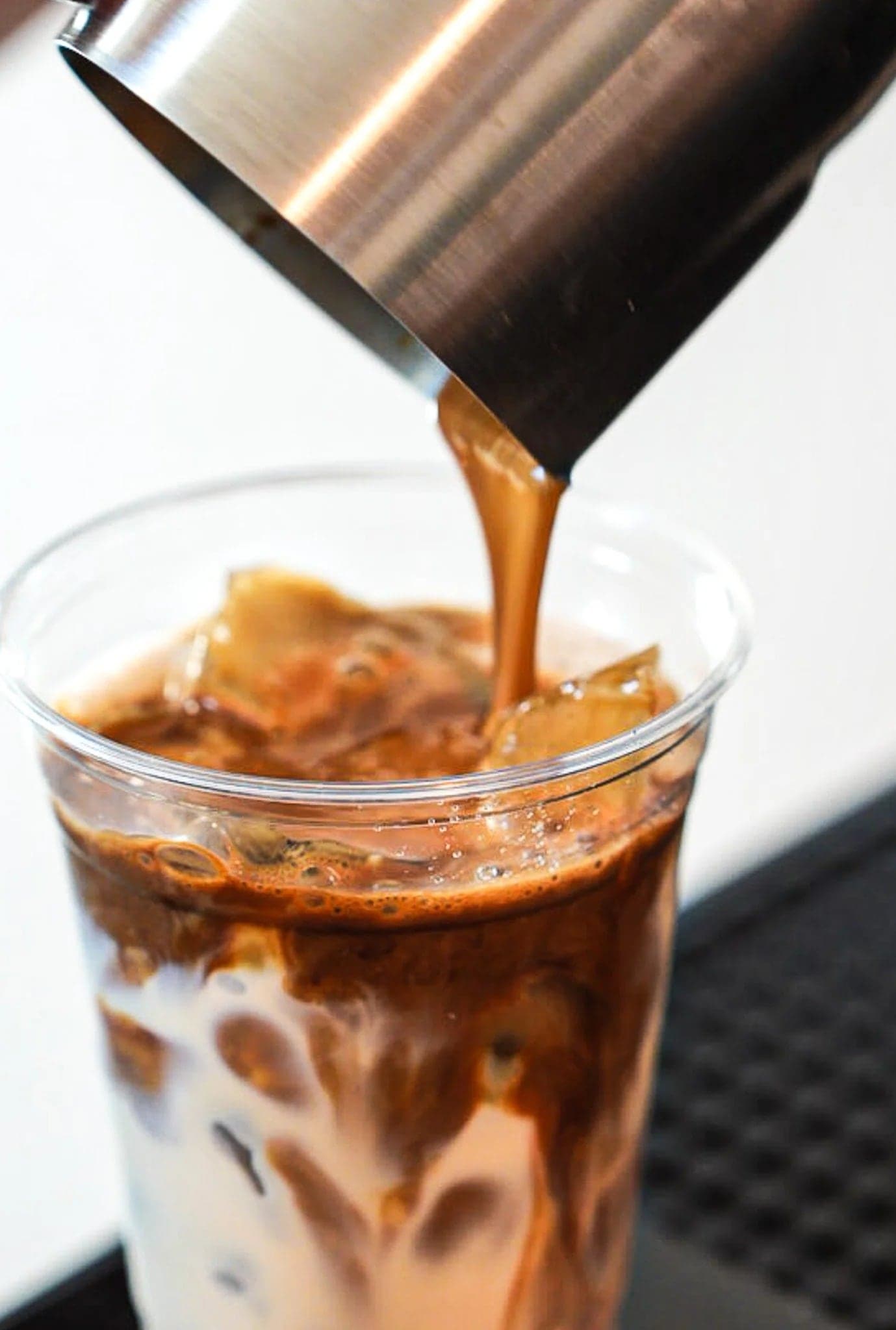 Espresso poured over an iced latte, caught mid swirl